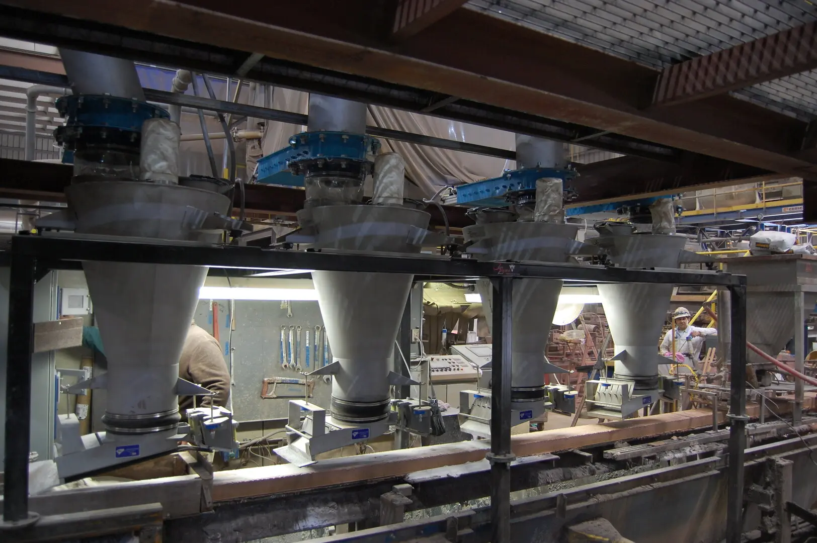 Multiple loss-in-weight vibratory feeders above a sand coating line
